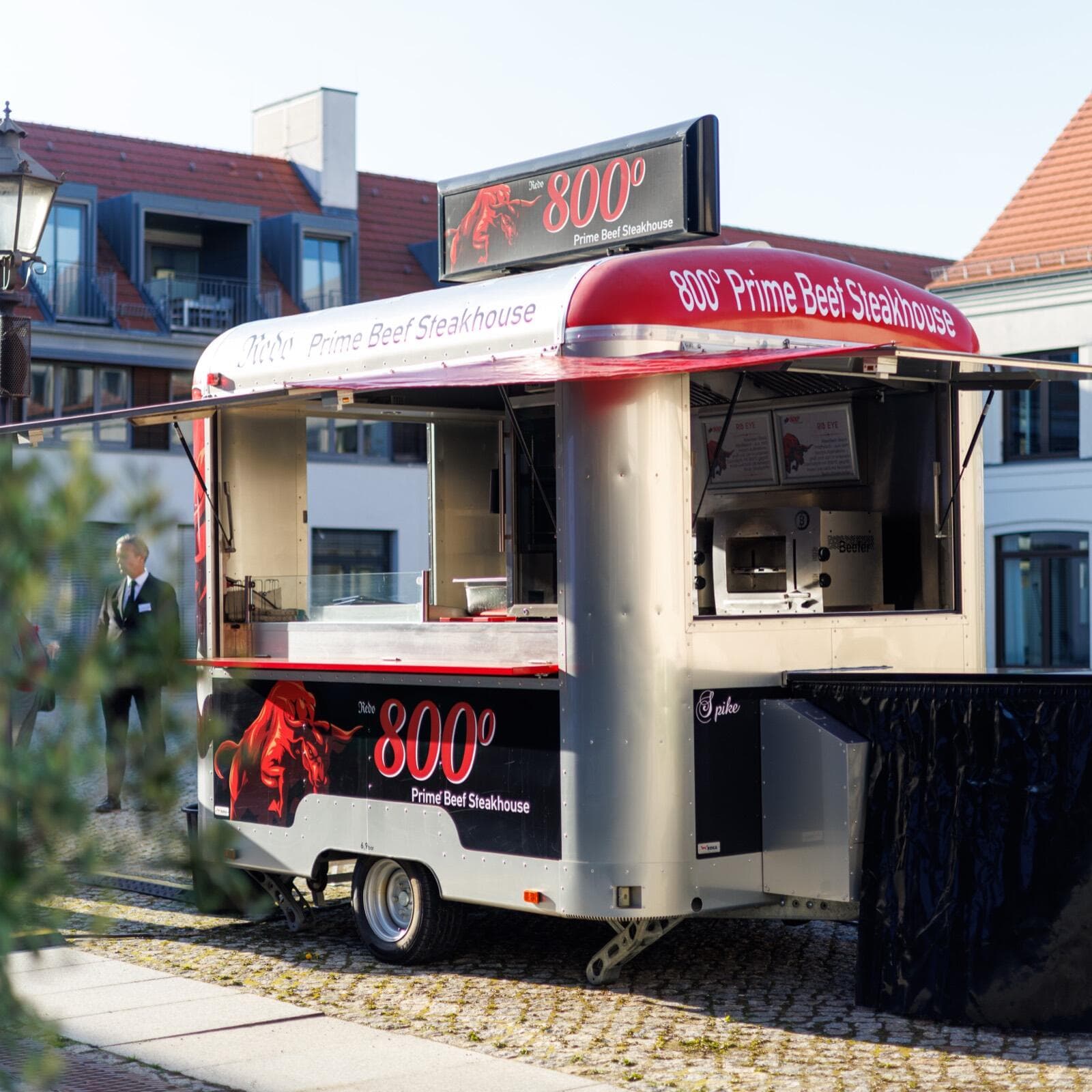 Der silberne Foodtruck des 800 Grad Prime Beef Steakhouse mit rotem Dach und offener Verkaufsklappe